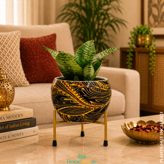 Black and golden abstract metal planter with green snake plant on a gold metal stand, styled in a modern home decor setting