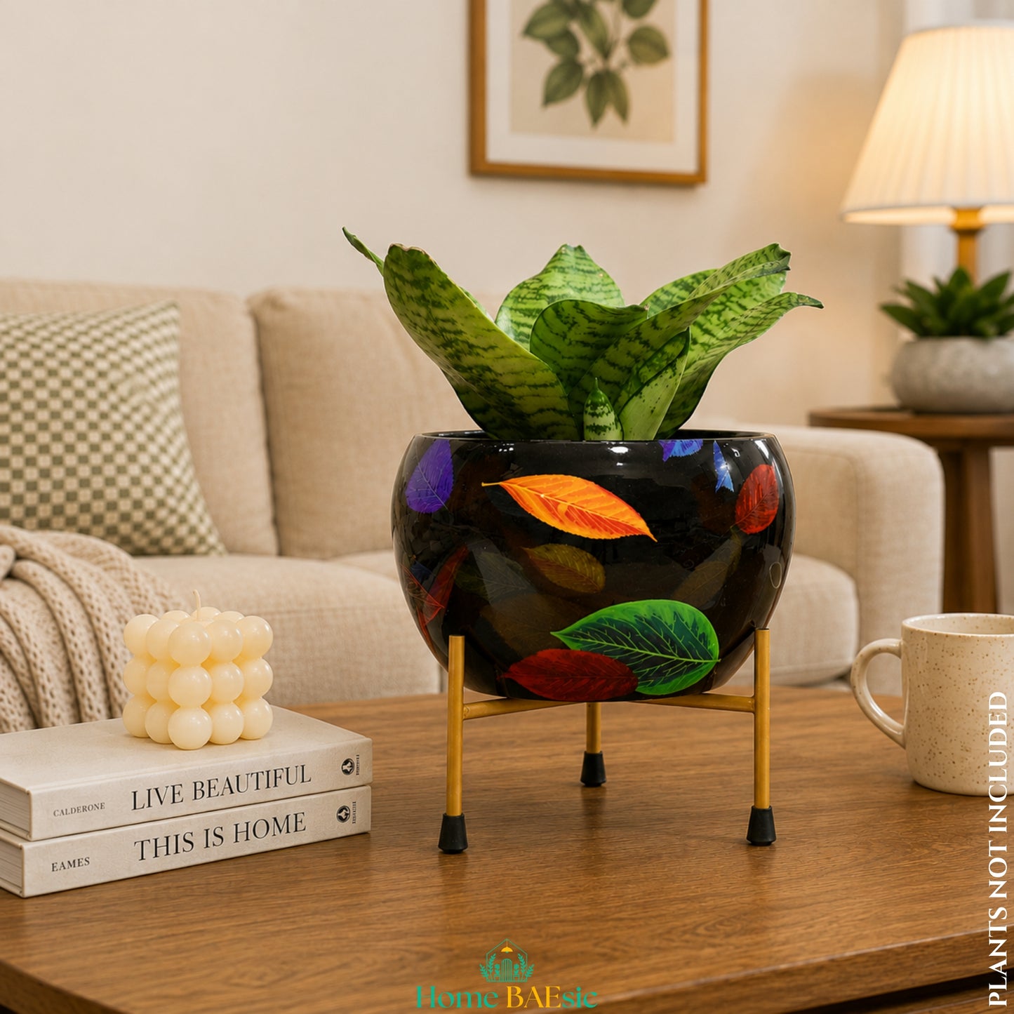 Falling Leaves black metal planter with colorful leaf design on a golden metal stand styled on a living room table