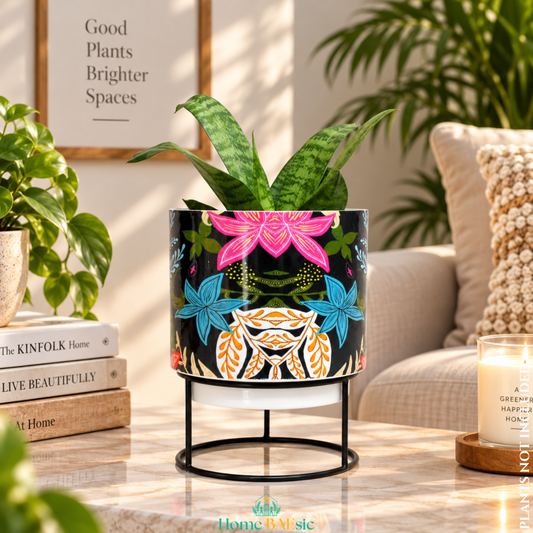 Floral Fantasy designer metal tumbler planter with stand, featuring vibrant multicolor floral artwork and a green indoor plant, styled as an elegant home decor accent.