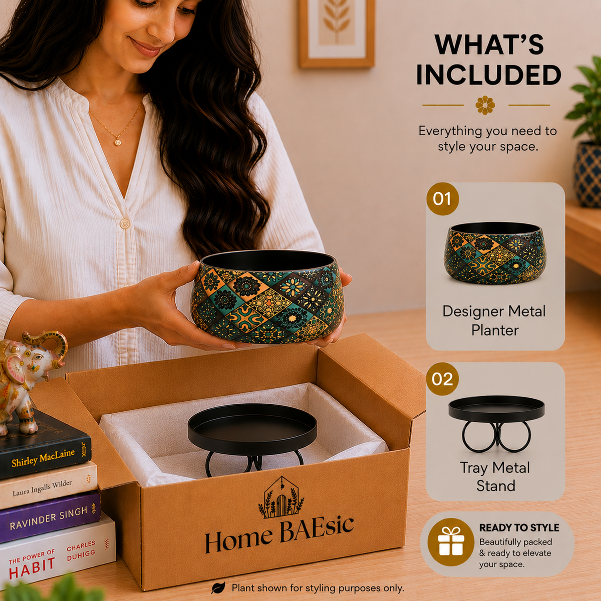 A woman holds a decorative metal planter bowl above an open Home BAEsic box, with a tray metal stand inside and a 'What's Included' graphic overlay on the right. The planter has a black base with intricate gold, green, and teal geometric patterns.