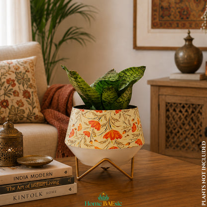 Happy Poppy floral metal planter with orange flower design and golden stand styled with an indoor snake plant in a modern Indian living room