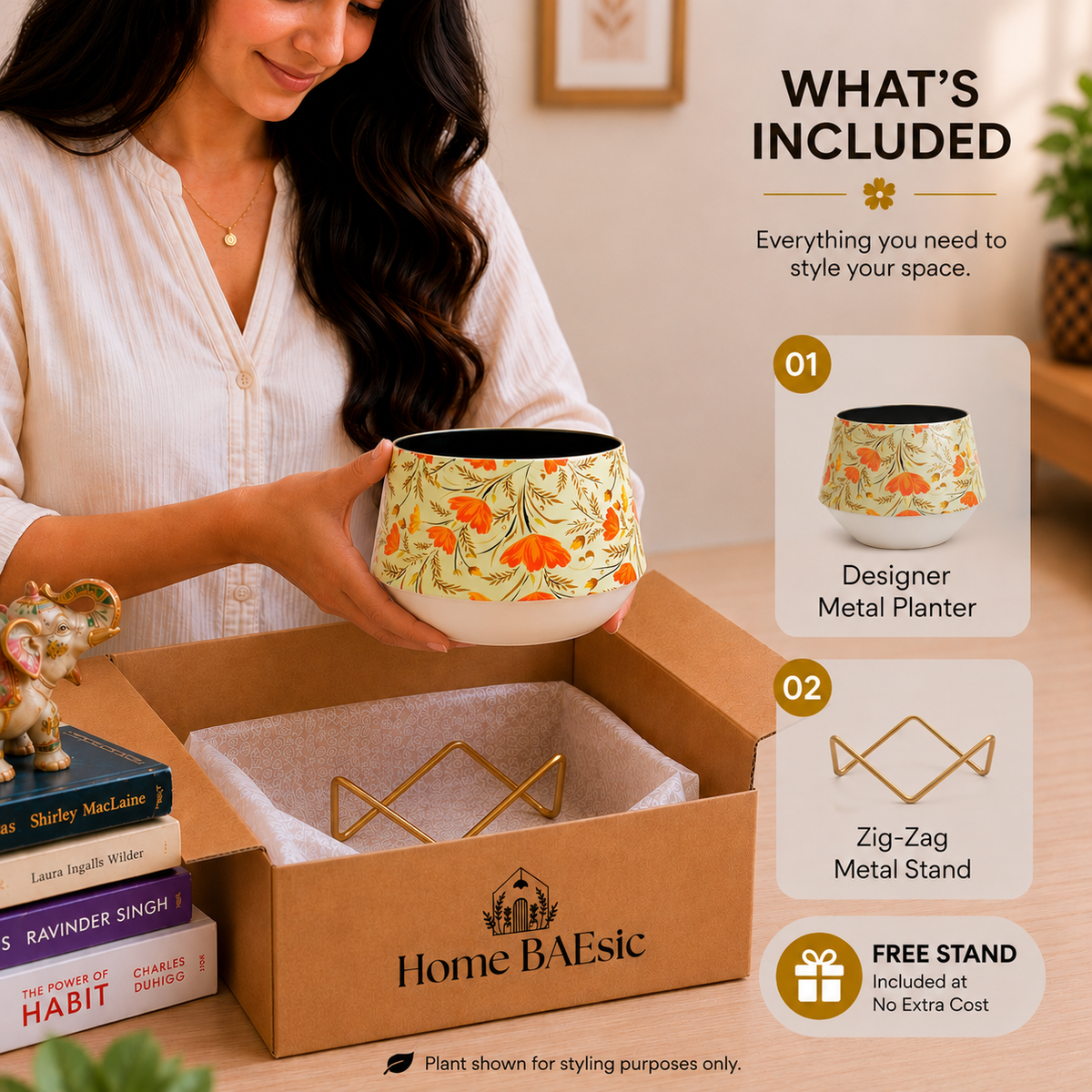 A woman holds a floral metal planter pot above an open Home BAEsic box, with included accessories and a 'What's Included' graphic shown on the right. The planter has a cream base with a yellow, orange, and green botanical pattern, and the set includes a gold zig-zag metal stand.