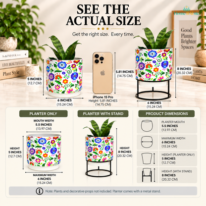 size guide for Home BAEsic Multifloral Tumbler Metal Planter, showing the colorful floral planter with and without its black metal stand, an iPhone 15 Pro for size reference, and dimensions of 6 inches wide, 5 inches high for the planter, and 8 inches high with stand. The infographic also highlights the 5.5-inch planter mouth and notes that plants and decorative props are not included.