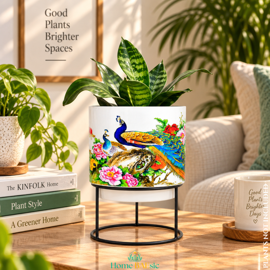 Peacocks in Garden designer metal tumbler planter with stand, featuring colorful peacock and floral artwork with a green indoor plant.