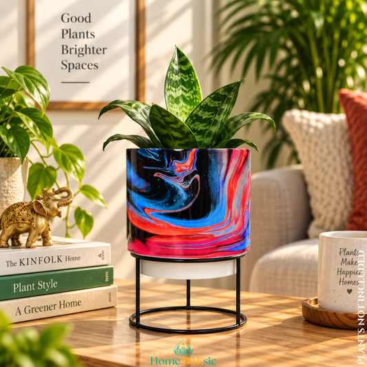Rosso Storm designer metal tumbler planter with stand, featuring bold black, red, pink and blue marbled artwork with a green indoor plant.